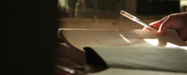 Hand holding a pen over softly lit pages, symbolising reflection, care, and the quiet changes shaping therapy.