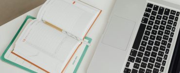 Open notebook and laptop on a clean desk, symbolising balance between human care and technology in therapy.