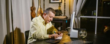 Therapist writing notes in soft evening light, symbolising the unseen effort and time that manual documentation requires